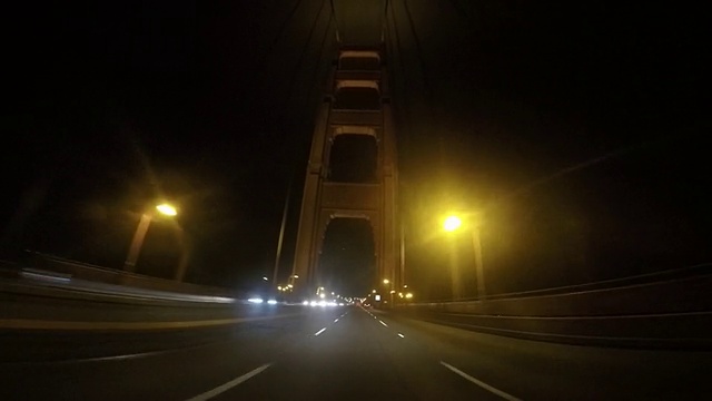 一辆车在晚上驶过金门大桥。视频素材