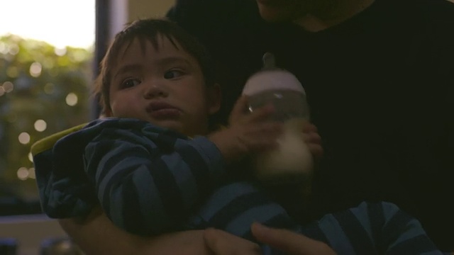 婴儿在妈妈的臂弯里哭泣，妈妈把婴儿传给爸爸的臂弯背上婴儿，靠近婴儿/美国加州洛杉矶视频下载
