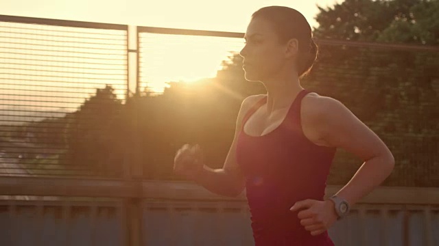SLO MO TS女人在日落时在城市里跑步视频素材