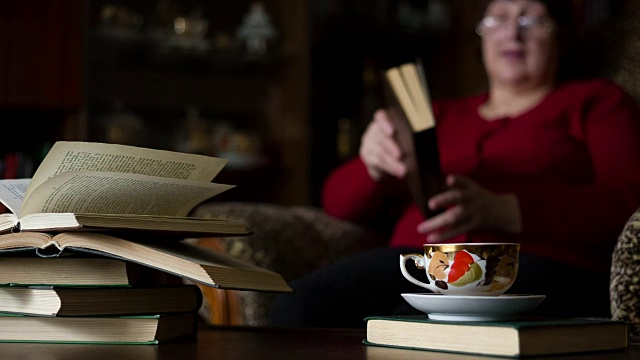 女人读小说。桌子上有书和一杯茶。视频素材