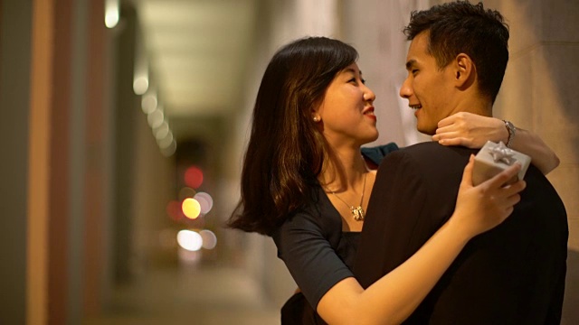 年轻的夫妇晚上在街上拥抱。视频购买