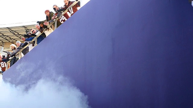 在比赛开始前，当职业足球队穿过迷雾冲出体育场隧道时，球迷们欢呼雀跃视频素材