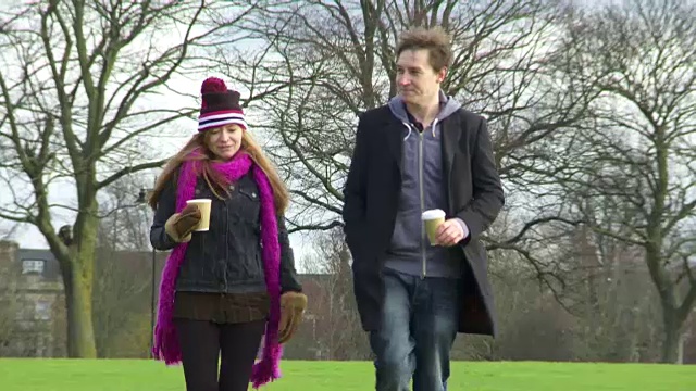(中景)一个男孩和一个女孩一起走过一个公园视频素材