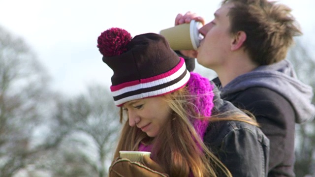 拉焦点一对夫妇在公园里喝咖啡聊天在冬天宽镜头视频素材
