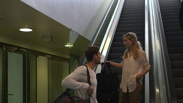 一对夫妇正沿着车站的扶梯往下走视频下载
