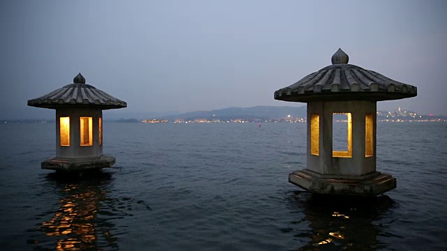 黄昏时分，中国杭州西湖上的一对被照亮的石灯笼视频下载