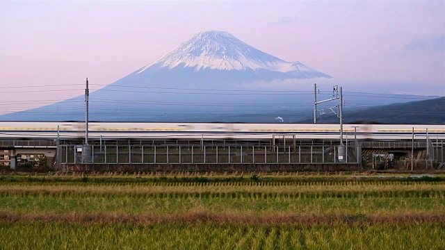 日本，本州，富士山，新干线子弹列车通过收获的稻田下的积雪覆盖的火山视频素材