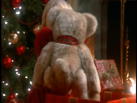金发小女孩从盒子里拿出毛绒熊，抱在客厅的圣诞树旁视频素材