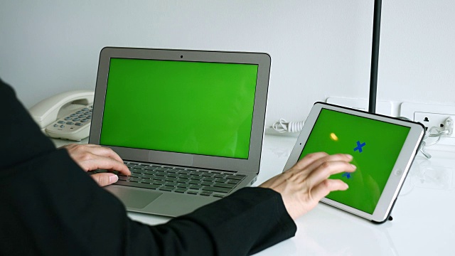 这是一位女商人用绿色屏幕的笔记本电脑和数码平板电脑工作的照片，4k超高清视频下载