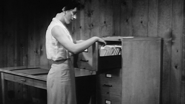 1957年妇女打开文件柜+在办公室里查看文件视频素材