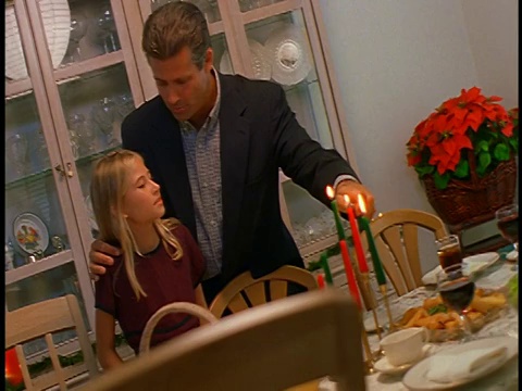 CANTED多莉拍摄的男人和女孩点燃蜡烛的桌子上的食物在圣诞节视频素材