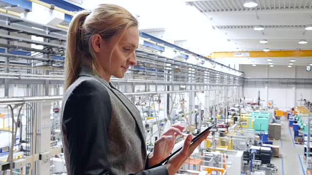 女商人在未来的工厂里研究平板电脑视频下载