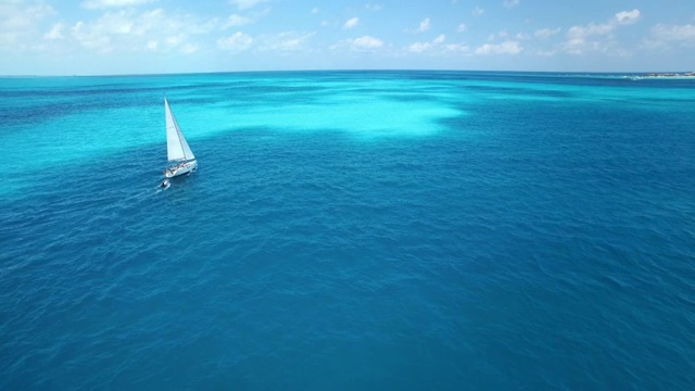 航拍帆船航行到美丽清澈的蓝色热带海洋的地平线上视频购买
