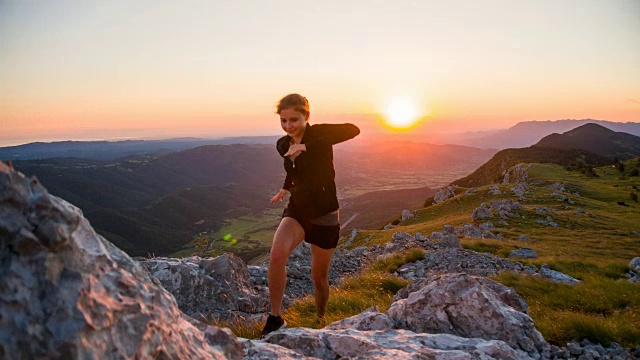 女运动员在日落时在山区岩石地形上跑步视频素材