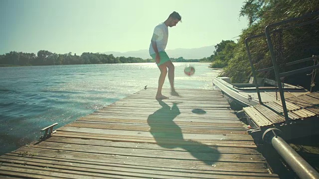 夏天的时候，一个男人在木制的防波堤上踢足球。年轻人耍球。For the Love of the Game: Soccer/Futbol视频购买