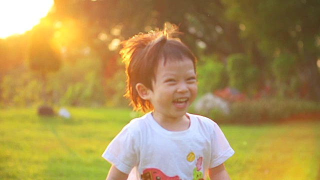 在夕阳的背景下，快乐的小男孩在公园里奔跑。视频素材