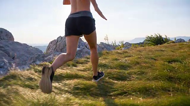 年轻的女跑步者在山上的草地上训练视频素材