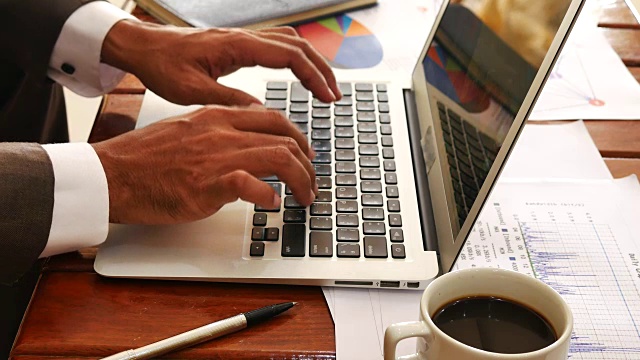 商人用手在笔记本电脑上敲着一杯咖啡工作视频素材