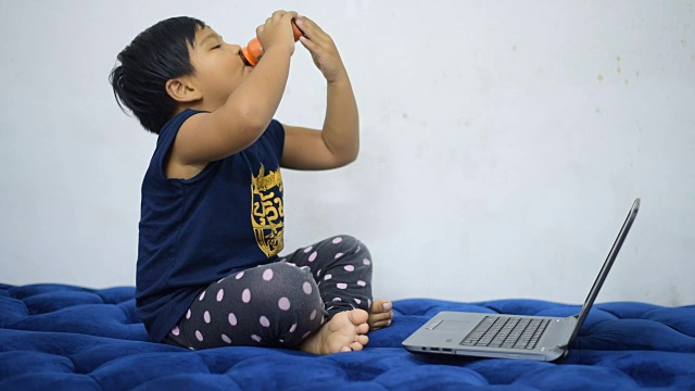 孩子喝大脑看笔记本电脑娱乐。视频素材