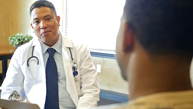 成熟的亚洲医生与年轻的非洲裔美国男性病人谈话视频下载
