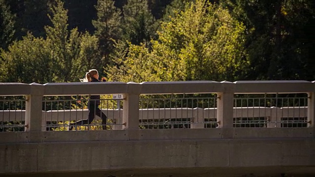 年轻女子在桥上跑步视频素材
