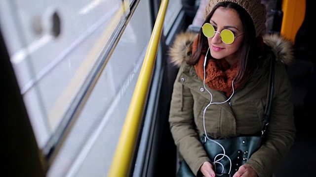 一个女人在无轨电车上用智能手机听音乐视频购买