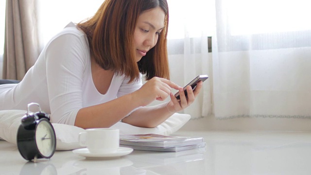 年轻女子在家里用智能手机和咖啡休息时间放松视频素材