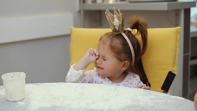 可爱的小女孩戴着皇冠在桌上玩面粉视频下载