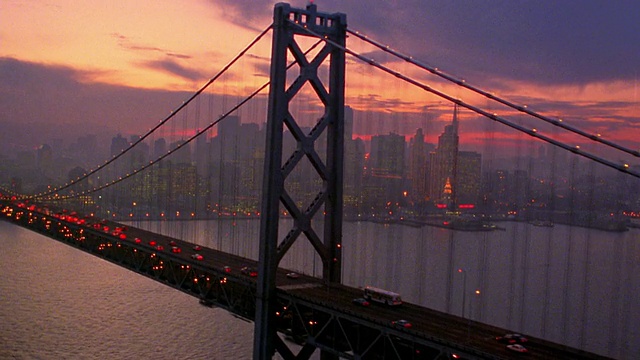空中侧面的视角中型拍摄沿海湾大桥与交通在黄昏/平底宽拍摄天际线/旧金山，加利福尼亚视频素材
