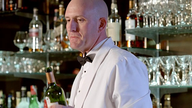 在高档酒吧的吧台上，MS调酒师把红酒从瓶子里倒进酒杯里视频素材