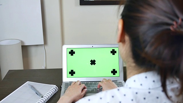 越过肩膀的女人使用笔记本电脑与绿色屏幕，色度键视频素材