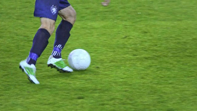 SLO MO足球运动员带球穿过球场的双腿视频下载