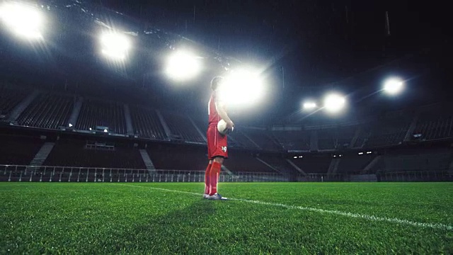 一个足球运动员在一个空的体育场拿着一个球的肖像视频下载