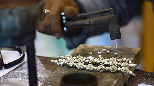 男人手工制作的银项链用煤气燃烧来粘合视频下载