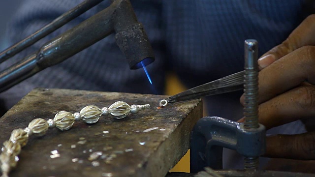 男人手工制作的银项链用煤气燃烧来粘合视频下载