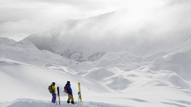 两个偏远地区的滑雪者在白雪覆盖的山顶上视频素材