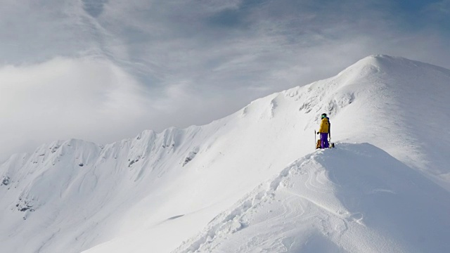 两个偏远地区的滑雪者在白雪皑皑的山脊上举起双手视频素材