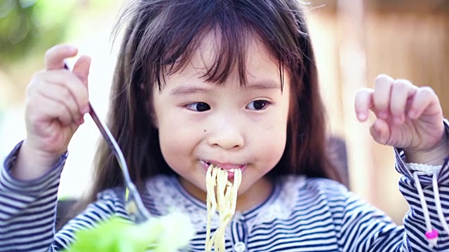小女孩在吃美味的意大利面。视频素材