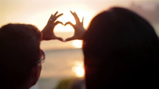 日落时分，在依帕内玛的海滩上，情侣们手拉手制作心形视频下载