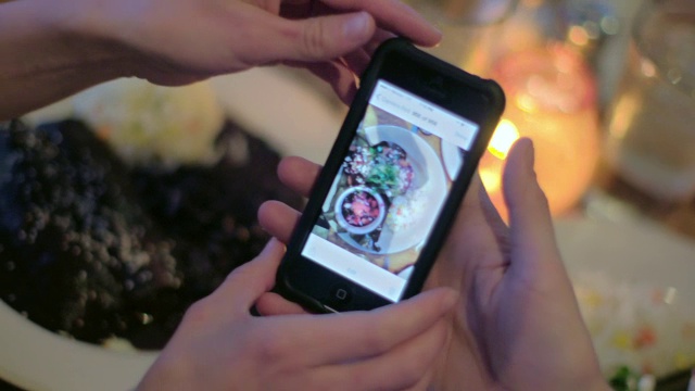 一个年轻人在餐馆里把自己的盘子拍了下来，和朋友分享视频下载