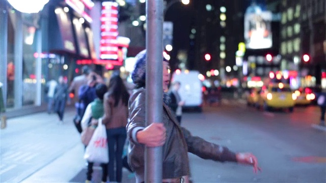 在时代广场的中心，一个恋爱中的年轻女子在街道指示牌旁摇摆视频下载