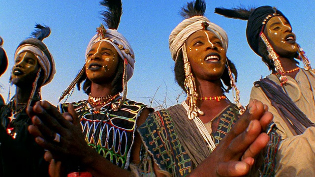 低角度中镜头拍摄的沃达贝斯在婚礼上穿着部落服装，脸上涂着油彩和带羽毛的头巾鼓掌/尼日尔视频下载