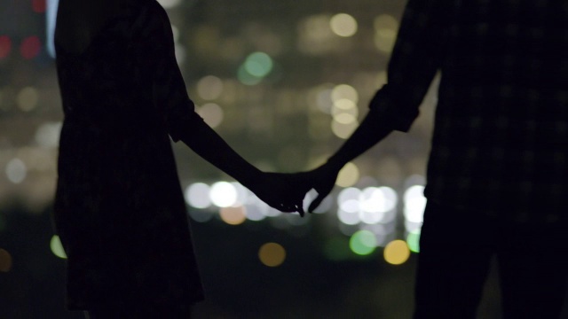 年轻夫妇手牵着手俯瞰城市的天际线视频下载