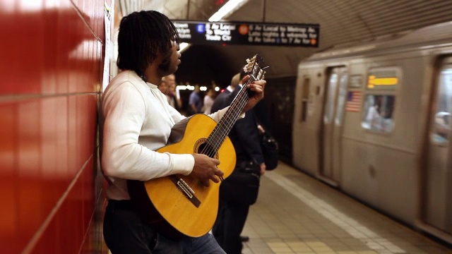 MED侧写黑人靠在红墙弹吉他在地铁站列车进入乘客登机视频下载