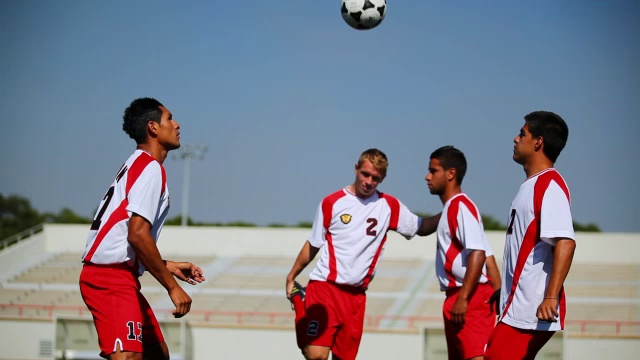足球运动员在足球场上一起练习踢腿和头部碰撞。视频素材