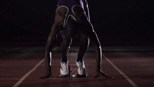 运动员以起跑姿势蹲下后沿着跑道跑。视频素材