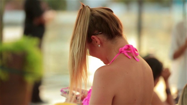 穿着粉色比基尼的女孩在里约热内卢泳池边用智能手机跳舞发短信视频素材
