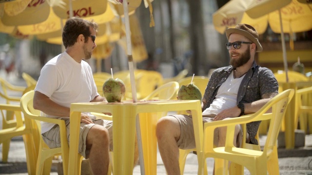 朋友们在阳光明媚的户外咖啡馆边谈边喝椰子视频下载
