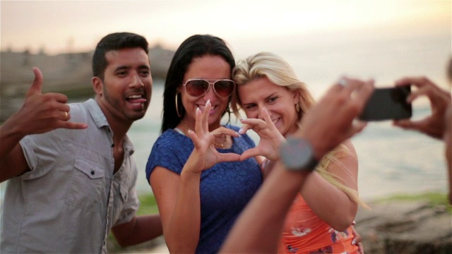 日落时分，朋友们在依帕内玛海滩上用智能手机拍照视频素材