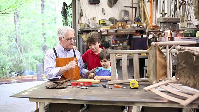 孙子在车间里，爷爷在修理古董家具。视频素材